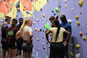 People standing by a purple rock climbing wall.