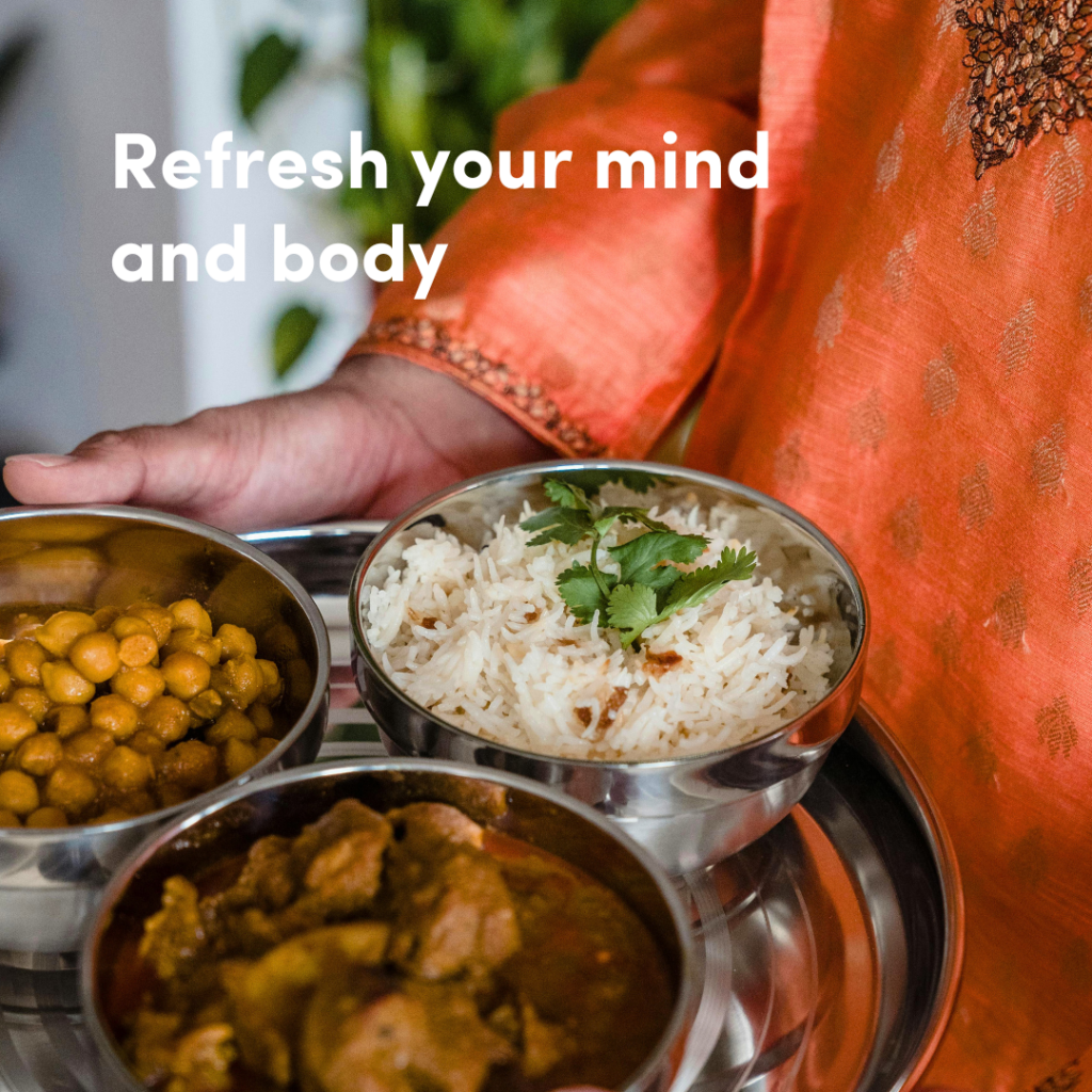 Someone wearing an orange top holding plates of Indian food, with the text 'Refresh your mind and body.'